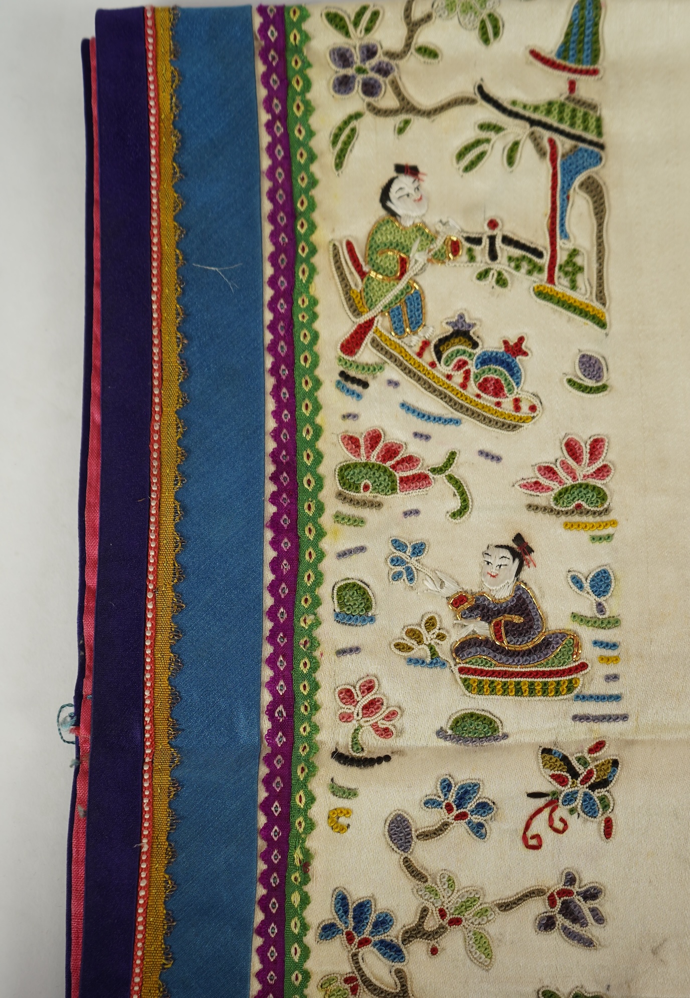 A Chinese embroidered silk panel of uncut robe borders, eleven similar sleeve panels and two other items, late Qing dynasty